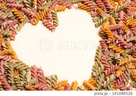 Rice vegetable pasta on a white background, laid out in the shape of a heart, a place for text. Rice vegetable pasta on a white background, laid out in the shape of a heart, a place for text. 101086526