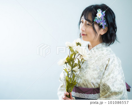 手に花を持ち、洋風な花柄小紋（着物）を着る女性：白背景 101086557