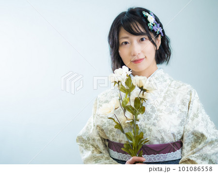 手に花を持ち、洋風な花柄小紋（着物）を着る女性：白背景 101086558