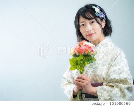 手に花を持ち、洋風な花柄小紋（着物）を着る女性：白背景 101086560