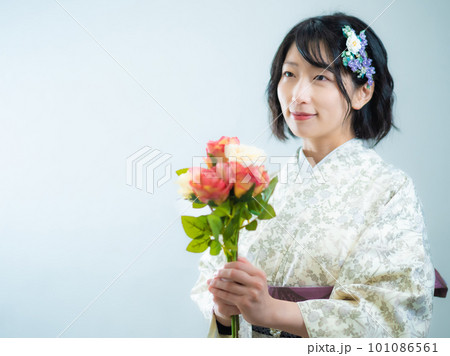 手に花を持ち、洋風な花柄小紋（着物）を着る女性：白背景 101086561