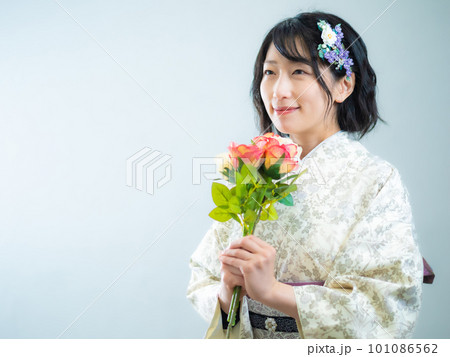 手に花を持ち、洋風な花柄小紋（着物）を着る女性：白背景 101086562