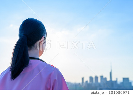 都会の街並みの景色を見るスクラブを着た女性看護師の後ろ姿 医療従事者 医師 介護士 就職 福岡遠景 都会の街並みの景色を見るスクラブを着た女性看護師の後ろ姿 医療従事者 医師 介護士 就職 福岡遠景 101086971