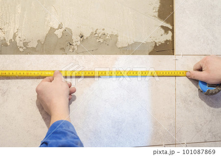 Workers hands and measuring tape. Construction repair work in the room for laying ceramic tiles 101087869