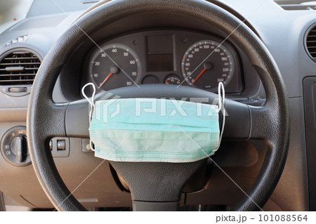 Medical protective mask on the steering wheel of a car. Healthcare and medicine concept 101088564