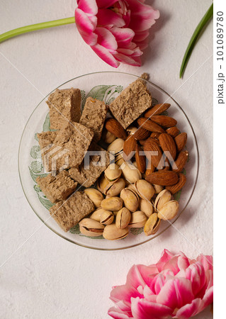 Pistachio, almond and halva on a transparent plate on a light background Pistachio, almond and halva on a transparent plate on a light background 101089780
