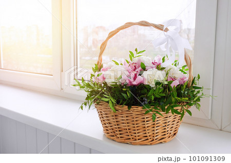 A basket of colorful flowers stands by the window on a sunny day. Chrysanthemum, carnation A basket of colorful flowers stands by the window on a sunny day. Chrysanthemum, carnation 101091309