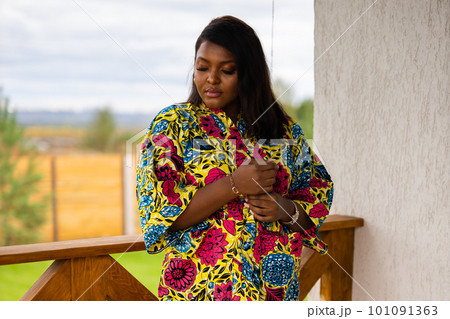 Beautiful african american woman enjoying evening on village and nature on terrace of country house. Diversity and inclusion and cottagecore concept Beautiful african american woman enjoying evening on village and nature on terrace of country house. Diversity and inclusion and cottagecore concept 101091363