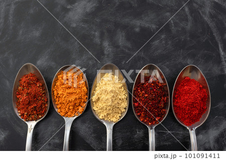 Spoons with seasonings and spices on a dark background. Top view 101091411