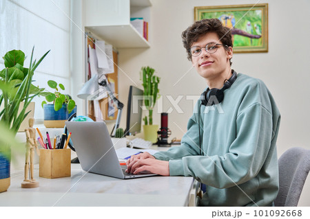 Young male college student sitting at desk at home using laptop Young male college student sitting at desk at home using laptop 101092668