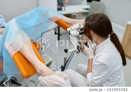 Gynecologist examining patient on chair with gynecological equipment 101093283