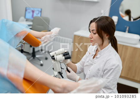 Gynecologist examining patient on chair with gynecological microscope 101093285