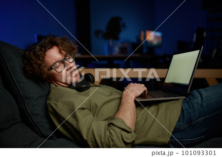 Tired system administrator sleeping under laptop computer on sofa at server room 101093301
