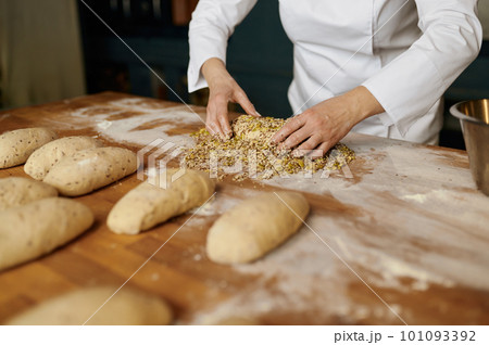 Portrait of positive female baker shaping bread bagels with seeds 101093392