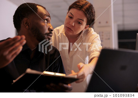 Analyst helping colleague analyzing report statistics, comparing data on laptop in office. Two corporate workers checking marketing research results in coworking space at night Analyst helping colleague analyzing report statistics, comparing data on laptop in office. Two corporate workers checking marketing research results in coworking space at night 101093834