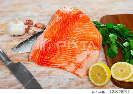 Raw salmon fillet with lemon and greens before cooking 101096767