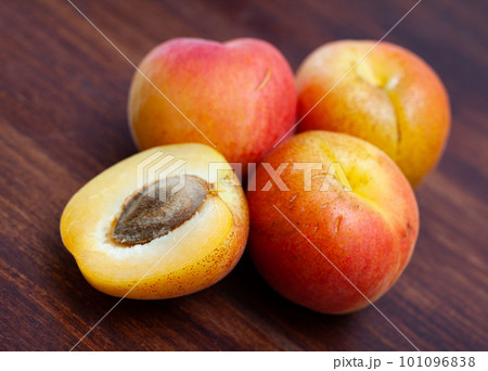 Ripe whole apricots and halves on wooden surface 101096838