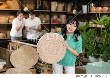 girl examines round pillow made of wicker for garden furniture before buying girl examines round pillow made of wicker for garden furniture before buying 101097033