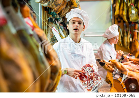 Male seller offering sliced bacon in butcher shop 101097069