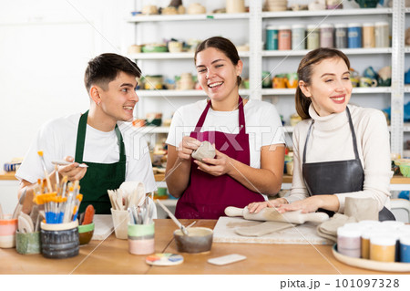 Joyous young man and women sculpting handmade cups 101097328