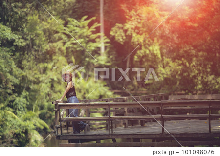 woman standing on wooden patio against deep green forest woman standing on wooden patio against deep green forest 101098026