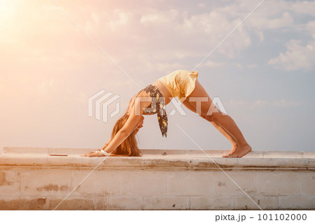Woman park yoga. Side view of free calm bliss satisfied woman with long hair standing in morning park with yoga position against of sky by the sea. Healthy lifestyle outdoors in park, fitness concept. 101102000