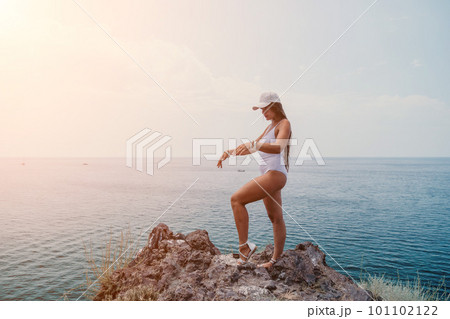 Woman travel sea. Happy tourist in hat enjoy taking picture outdoors for memories. Woman traveler posing on the beach at sea surrounded by volcanic mountains, sharing travel adventure journey Woman travel sea. Happy tourist in hat enjoy taking picture outdoors for memories. Woman traveler posing on the beach at sea surrounded by volcanic mountains, sharing travel adventure journey 101102122