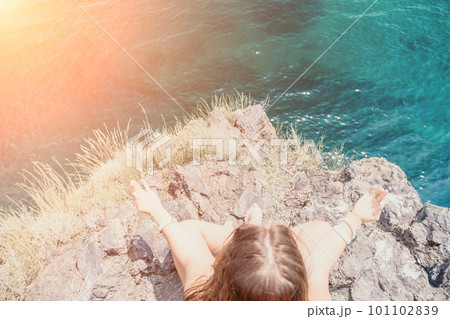 Woman sea yoga. Back view of free calm bliss satisfied woman with long hair standing on top rock with yoga position against of sky by the sea. Healthy lifestyle outdoors in nature, fitness concept. 101102839