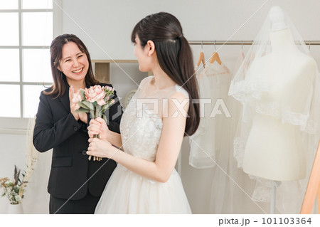 ウェディングドレスを試着・フィッティングする花嫁とウェディングプランナーの女性 ウェディングドレスを試着・フィッティングする花嫁とウェディングプランナーの女性 101103364