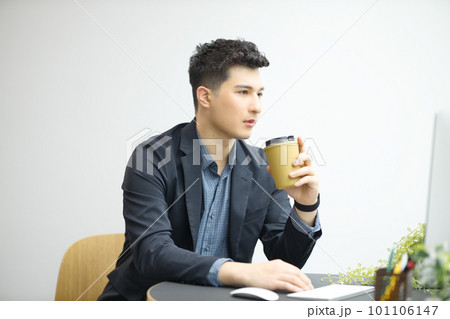 コーヒーを飲みながらパソコンを見る若い男性 101106147