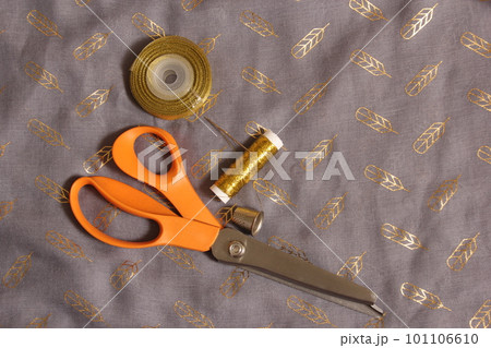 Spool of Metallic Gold Thread on Gray and Gold Chiffon Fabric Spool of Metallic Gold Thread on Gray and Gold Chiffon Fabric 101106610