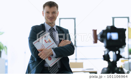 Successful businessman coach with documents with graphs in hands standing near camera in office Successful businessman coach with documents with graphs in hands standing near camera in office 101106964