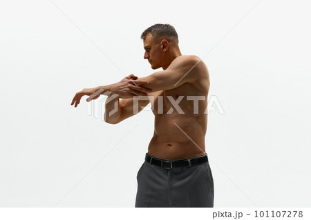 Shot of attractive man wearing pants standing shirtless and posing at camera over white background. Sporty body Shot of attractive man wearing pants standing shirtless and posing at camera over white background. Sporty body 101107278