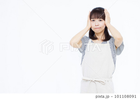 頭を抱えて悩むエプロン姿の30代主婦 頭を抱えて悩むエプロン姿の30代主婦 101108091