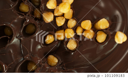 Close-up of Falling Whole Hazelnuts into Melted Chocolate 101109183