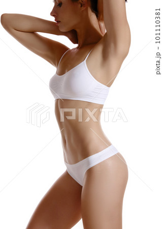 Perfect, slim, toned, young body of a girl in white underwear posing isolated on white. Plastic surgery and aesthetic cosmetology concept. Close-up. Perfect, slim, toned, young body of a girl in white underwear posing isolated on white. Plastic surgery and aesthetic cosmetology concept. Close-up. 101110381
