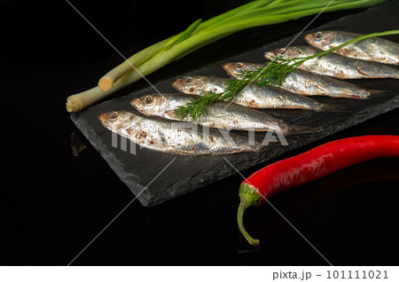Sprat with vegetables on a serving board. Small salted fish with onion and pepper. Delicious dinner idea. 101111021