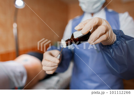Doctor woman holds tweezers in her hands and drips on the cotton wool antibacterial solution. It is used in the treatment of wounds. Antiseptic impregnation. Doctor woman holds tweezers in her hands and drips on the cotton wool antibacterial solution. It is used in the treatment of wounds. Antiseptic impregnation. 101112266