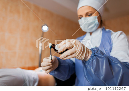 Nurse holds in hands tweezers and drips an antibacterial solution on cotton wool of brilliant green alcohol on cotton wool. Used in inflammatory skin diseases. Close-up Nurse holds in hands tweezers and drips an antibacterial solution on cotton wool of brilliant green alcohol on cotton wool. Used in inflammatory skin diseases. Close-up 101112267