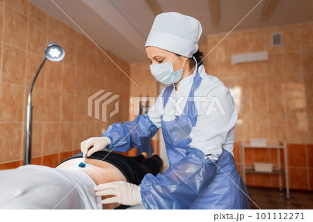 Doctor in medical uniform lubricates the wound with a brilliant-green antibacterial solution to heal wounds after surgery. Nurse caring for patient in hospital. Doctor in medical uniform lubricates the wound with a brilliant-green antibacterial solution to heal wounds after surgery. Nurse caring for patient in hospital. 101112271