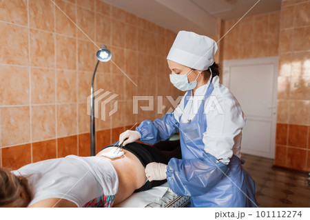 Professional nurse changes the dressing to a patient who is lying on a couch in the emergency room. Bruised back. Back injury. Professional nurse changes the dressing to a patient who is lying on a couch in the emergency room. Bruised back. Back injury. 101112274