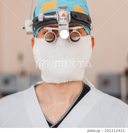 Young neurosurgeon man in a medical mask with professional magnifying glasses with binary loupes for microsurgery. Instruments for surgery Young neurosurgeon man in a medical mask with professional magnifying glasses with binary loupes for microsurgery. Instruments for surgery 101112422