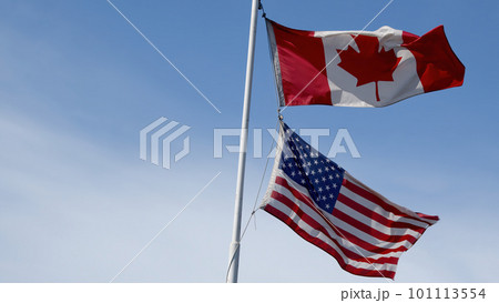 canada and usa flags fluttering in the wind on blue sky copy space blue sky background 101113554