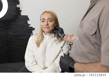 Doctor pulls female facial skin, lifting temple area, preparing to face reshape with filler, injection, surgery. Beauty physician, female patient are in examination room.Aesthetic medicine.Horizontal. Doctor pulls female facial skin, lifting temple area, preparing to face reshape with filler, injection, surgery. Beauty physician, female patient are in examination room.Aesthetic medicine.Horizontal. 101113635