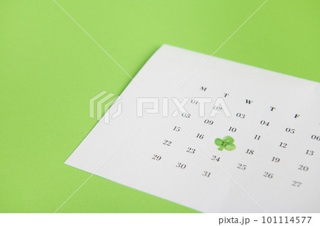 Still life with a white calendar marked with the date March 17- traditional Irish festival - Saint Patrick's Day, celebrated in Ireland, isolated on green background with free advertising space 101114577