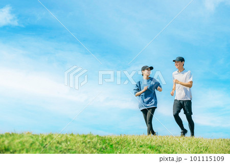 青空の下でジョギングをする笑顔の日本人男女 101115109