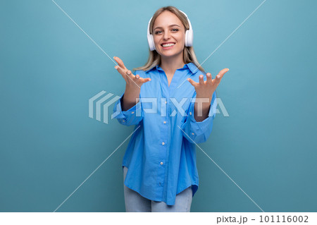 joyful lucky girl in big headphones without wire stretches out her hands on a blue background joyful lucky girl in big headphones without wire stretches out her hands on a blue background 101116002