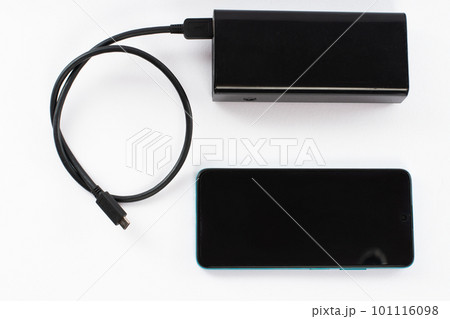 power bank with charging cable and phone, copy space and white background. 101116098