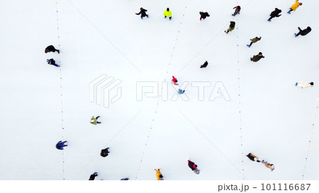 Many people skating on white ice skating rink outdoors on winter day top view. Aerial drone view. New Year Christmas celebration holidays recreation sport enjoying lifestyle sportive fun background. 101116687
