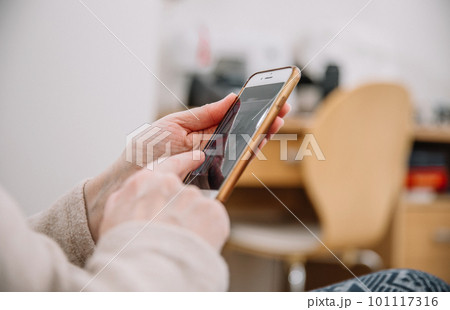 Elderly woman holding and using smartphone, mobile phone. Grandmother hands. Close up view, family connection concept Elderly woman holding and using smartphone, mobile phone. Grandmother hands. Close up view, family connection concept 101117316